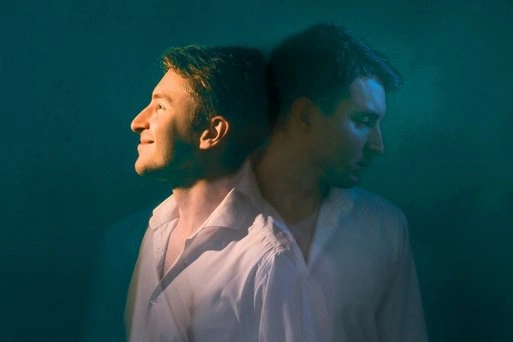 Man staring at his reflection in a mirror, representing emotional struggle linked to bipolar disorder