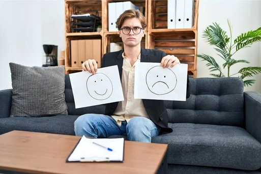 Woman standing indoors holding her head, appearing thoughtful and emotionally strained.