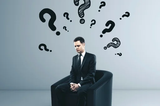 A man sitting in thought surrounded by question marks, symbolizing the doubt and confusion of OCD.