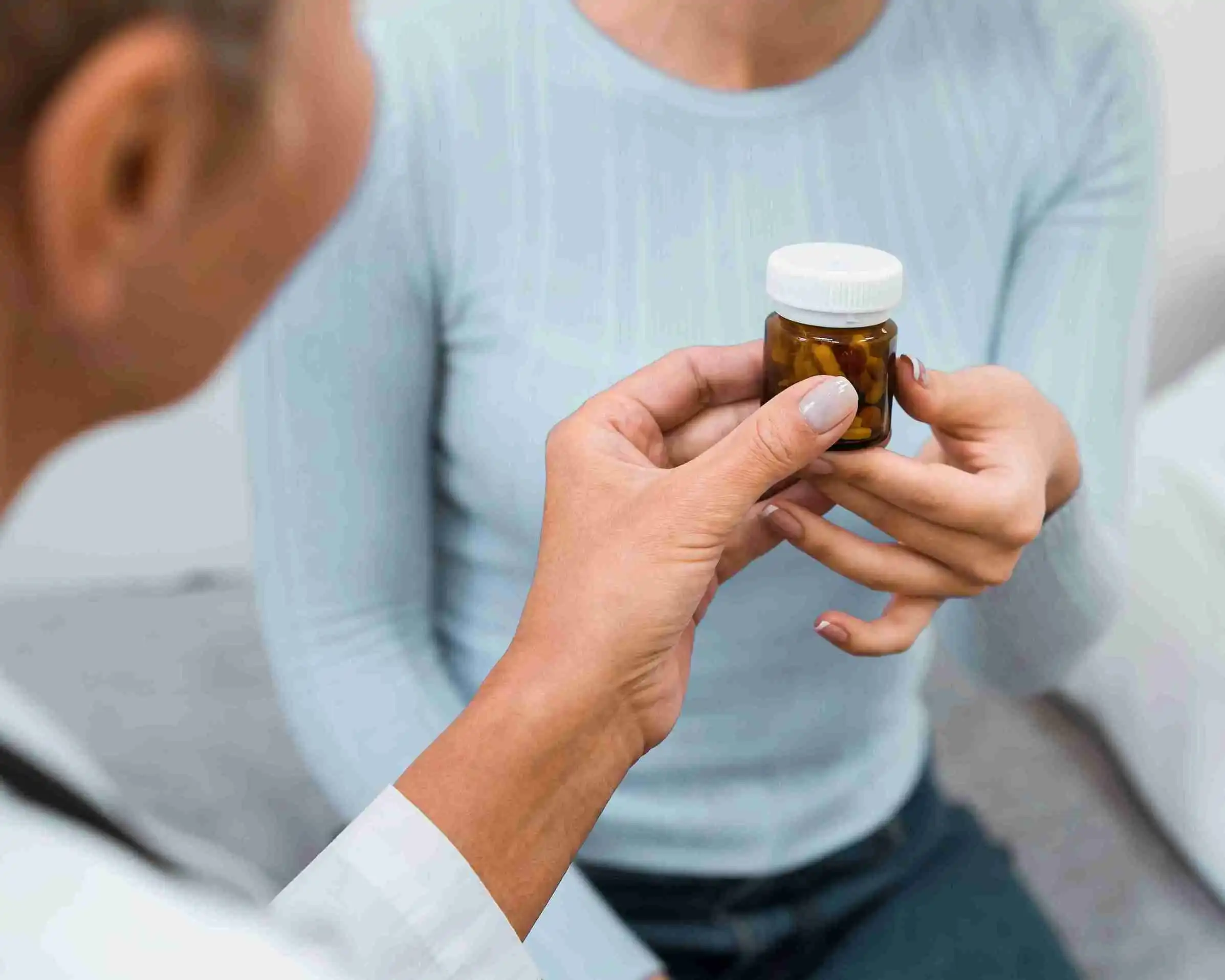 Psychiatrist handing a medication bottle to a patient during a psychiatric medication management consultation in Michigan