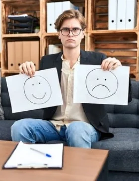 Woman standing indoors holding her head, appearing thoughtful and emotionally strained.
