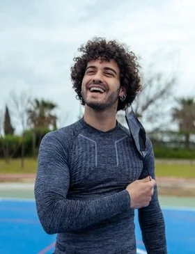 Smiling man outdoors, representing restored energy after healthy sleep and a refreshing morning walk