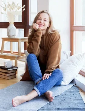 A young woman sitting by a window experiencing a shift in mood